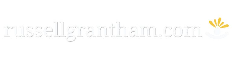 Text 'russellgrantham.com' in light grey lowercase letters, with a small, simple logo on the right: a white circle and arc and five yellow rays symbolising creative thought.